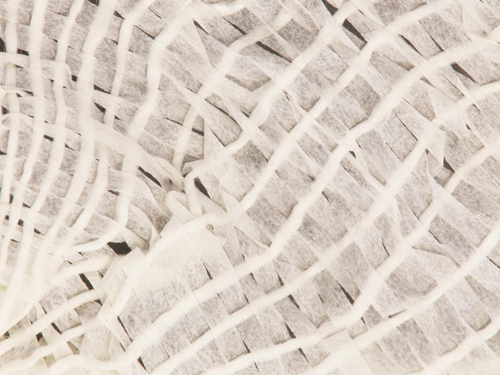 Up close shot of the weaving which is made of white waxed silk and paper strips. There are very small gaps in the weave. 